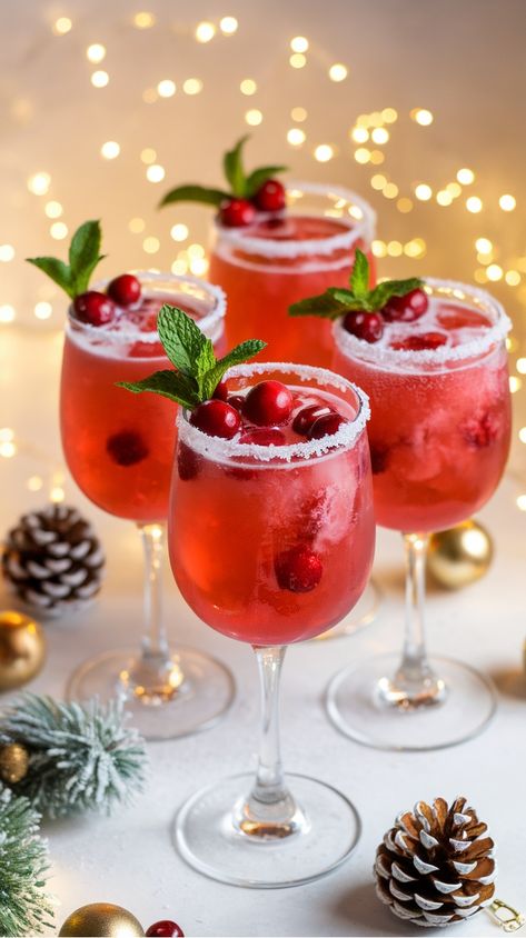 Festive cranberry cocktails in stemware, garnished with mint leaves and cranberries, surrounded by holiday decorations. Champagne Flute Desserts, Cranberry And Champagne Drink, Glitter Christmas Cocktails, Sparkling Cocktail Recipes, Cranberry Alcoholic Drinks Holidays, Winter Cranberry Cocktails, Holiday Prosecco Cocktails, Drink Recipes With Prosecco, Cranberry Prosecco Cocktail