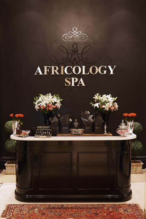 Reception area at the Africology Spa Dark Reception Desk, Beauty Salon Reception Ideas, Spa Reception Desk, Spa Reception Area, Salon Reception Area, Dark Wood Desk, Salon Interior Design Ideas, Nail Salon Interior Design, Beauty Salon Interior Design