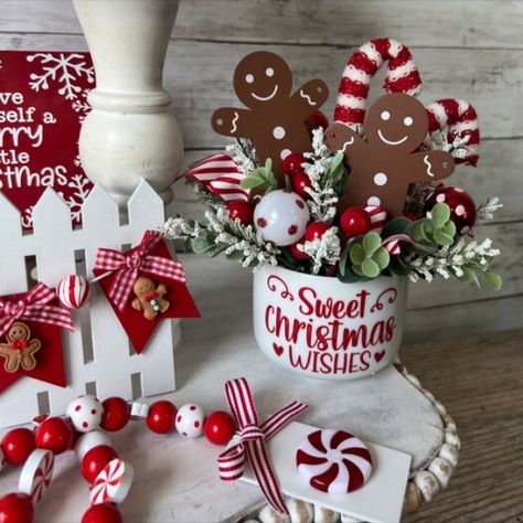 This white porcelain vase features faux eucalyptus and white astilbe florals. Faux candy canes, gingerbread men, mini christmas balls, and ribbon accents adorn each vase. A vinyl decal adorns the front and reads 'Sweet Christmas wishes'

Each vase measures 3 inches tall and 4 inches wide when empty. Once filled with the included faux arrangement, height is approximately 8 inches.

This listing is for 1 (one) vase filled with faux greenery and florals. Gingerbread Arrangements, Gingerbread Tiered Tray Decor, Gingerbread Tiered Tray, White Astilbe, Christmas Tiered Tray, Gingerbread Man Christmas, Faux Eucalyptus, Christmas Floral Arrangements, Faux Greenery