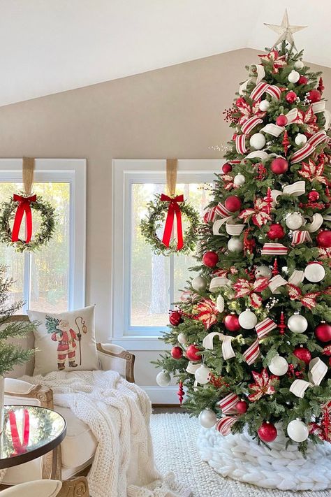 A Christmas tree decorated with red and white ornaments and ribbon, in front of windows with wreaths hanging in them with red bows. Candy Cane Home Decor, Red Snd White Christmas Tree, Christmas Styles Decor, Christmas Tree Decorations Red And White, Red Xmas Tree Decorating Ideas, Red Christmas Decor Ideas, Christmas Tree Red And White, Red Christmas Tree Decorations, Christmas Tree In Red