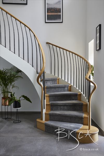 Curved staircase design with hand-forged metal balustrade, contrasting helical with straight and incorporating classical features, which perfectly integrate with the modern aesthetics of a new build property. Curved Staircase Design, Curved Staircase Handrail, Curvy Staircase, Metal Balustrade, Contemporary Curved Staircase, Curved Metal Staircase, Helical Staircase, Curved Glass Balustrade, Staircase Gallery