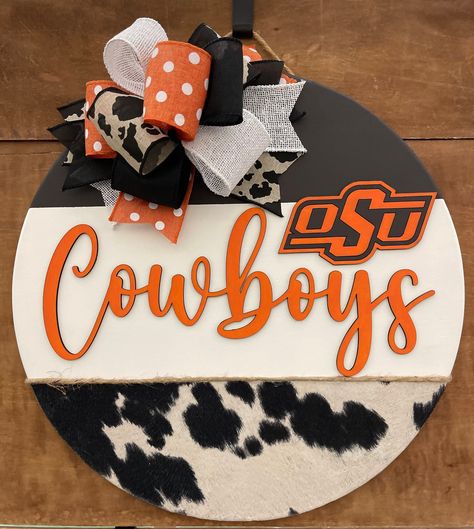 OSU Cowboys Door Hanger (Crafter License #2024103) Show your team spirit and let all your guests know you're a fan with this wooden door hanger! Display it all year long, during a specific sport season, or just on those special game days! (Inquire for other teams!) SIZE:  This sign is an 18-inch wood round door hanger. Thickness is 1/2 inch. WOOD:  This door hanger is made from real birch wood. There may be natural blemishes, wood grain and knots since it is real wood. This allows for the charac Door Hanger Display, Osu Cowboys, Round Door Hanger, Sports Wreaths, Special Games, Wooden Door Hanger, Small Nail, Print Bedroom, Oklahoma State University