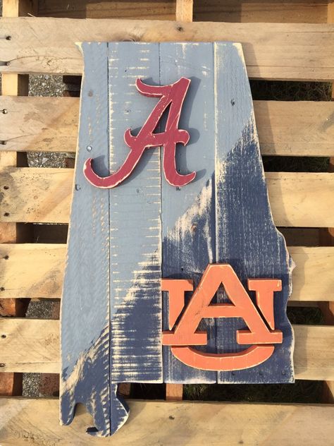 "Another unique creation from the original state sign company in Birmingham, AL finally being offered on Etsy.   This is the state shape of Alabama cut from reclaimed wood or pallets.  It is the House Divided sign with Alabama gray on the top half and Auburn blue on the lower half.  It features a crimson Alabama logo and an orange Auburn logo. The back has a strong wire hanger and features raised backing so it sits slightly raised off the wall when you hang it. The sign measures 26\" x 16\".  Ea Ga Football, Alabama Crafts, Barnwood Signs, Football Door Hangers, Wooden Pallet Crafts, Teal Home Decor, State Of Alabama, Alabama A, Auburn Alabama