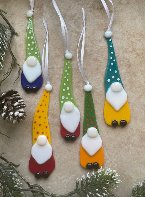 One gnome ornament. This adorable fused glass gnome is one of a kind! Each one is made by hand so no two are exactly alike. Your gnome color will be selected at random unless a specific color is requested. Each one has a tall hat with a pattern design, big nose and little black shoes! Since they are made and pieced together by hand, details of each gnome will vary. This ornament hangs from white ribbon. Approximate dimensions 5"x 1.5" Fused Glass Gnome Ornament, Fused Glass Christmas Gnomes, Fused Christmas Ornaments, Fused Glass Gnomes, Fused Glass Christmas Ornaments Ideas, Fused Glass Christmas Decorations, Glass Fusion Christmas, Glasfusing Ideas, Fused Glass Christmas Ornaments