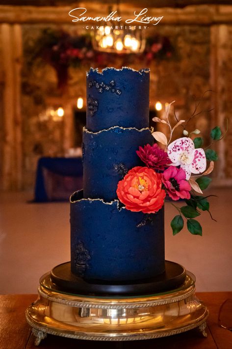 Textured midnight blue wedding cake with vibrant sugar flowers and gold trim Midnight Blue Wedding Cake, Midnight Blue Cake, Orange And Blue Wedding Cake, Wedding Cake Orange Flowers, Blue Red Wedding, Cod Cakes, Midnight Blue Wedding, Orange Wedding Cake, Wedding Cakes Blue