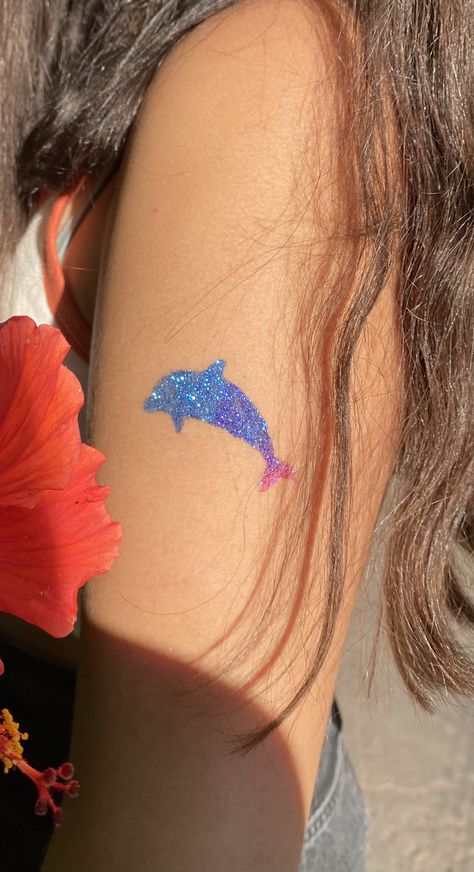 girls arm with a dolphin glitter tattoo on it. the tattoo is blue pink and purple Glitter Tattoo Aesthetic, Coconut Girl Tattoo, Glitter Tattoo Ideas, Beach Girlies, Bestie Crafts, Coconut Tattoo, Glitter Henna, Dolphin Tattoo, Sparkle Tattoo