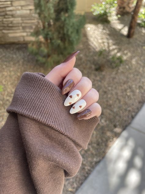 Chocolate brown nails with two white accent nails with small brown hearts 🤎 #nails #nailart #brownnails #brownaesthetic #heartnailart #heartdesign #heartnails #trendynailart #nailinspo #nailideas #almondnails #gelnails #gelpolish #gelextenstion Brown Nails Design Almond Shape, Cute Simple Brown Nails, Brown Hearts Nails, Brown Black And White Nails, Chocolate Nails Design Art Ideas, Brown Coquette Nails, Brown And White Acrylic Nails, Cute Brown Nail Ideas, Brown Cute Nails