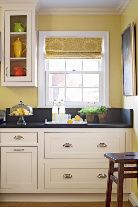 Creamy white cabinets are the hallmark of a traditional kitchen. Dark stone countertops and a coat of clean white paint allow this kitchen's charming Craftsman-inspired cabinetry to pop against a warm yellow wall color. #whitecabinets #kitchencabinets #kitchencolors #bhg Yellow Kitchens, Yellow Kitchen Walls, Kitchen Yellow, Kitchen Beautiful, Faux Granite, Painted Kitchen Cabinets Colors, Small Kitchen Layouts, Traditional Kitchen Design, Kabinet Dapur