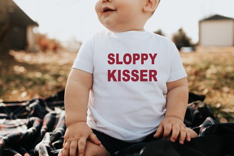 "Sloppy Kisser Infant/Toddler Tee. Perfect for your little valentine this February! SIZES: -6M -12M -18M -24M Red lettering on white shirt White lettering on black shirt \"xoxo\" detail on back of tee ----CHILD (TODDLER) SHIRT---- - Rabbit Skins Brand - Solid colors 100% cotton fine jersey - Heather is 90% cotton / 10% polyester - Colors may vary on your screen, due to the lighting in which the picture was taken and how your screen reads the colors. - Each item is sold separately. ----CARE INSTR Boys Valentines Outfit, Baby Valentines, Valentines Shirts, Outfit Baby Boy, Cricut Shirts, Heart Throb, Valentines Day Baby, Toddler Valentines, Valentine T Shirts