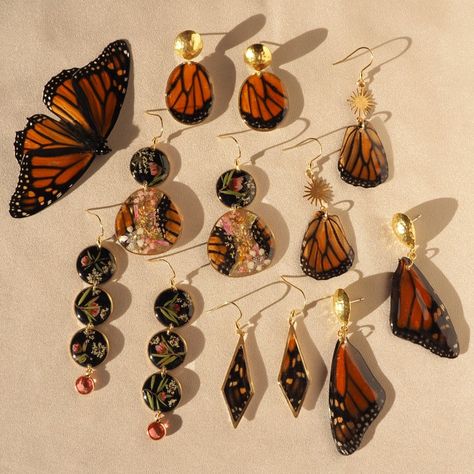 Earrings made from monarch Butterflies and flowers lying on silk in the sunshine next to a monarch Butterfly