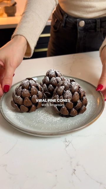 Georgina Thomas on Instagram: "Viral brownies pine cones! I had to jump on this trend and make the famous pine cones but with a gooey brownie centre using my brownies recipe. If you have any leftover brownies then this is such a cute idea for the holidays ✨🤎 Ingredients 9 brownies (see recipe on my page) Chocolate curl cereal 1-2 tbsp icing sugar Instructions 1. Make brownies (use my recipe on my profile- 2 posts down) or buy brownies! 2. Squeeze them together to form a pine cone shape. Around 9 brownies should make 6 cones. 3. Use as much cereal as you need to surround the brownie pine cones. This takes a while so be persistent! 4. Sieve with icing sugar and enjoy! #pinecones #pine #viral #chocolatebrownies #brownies #christmas #christmasdessert #holidays" Pine One Brownie, Brownie Pine Cones, Chocolate Pinecones Recipes, Leftover Brownies Ideas, Pine Cone Brownies, Brownie Pinecones, Pinecone Dessert, Pinecone Brownies, Christmas Cookie Trays Ideas