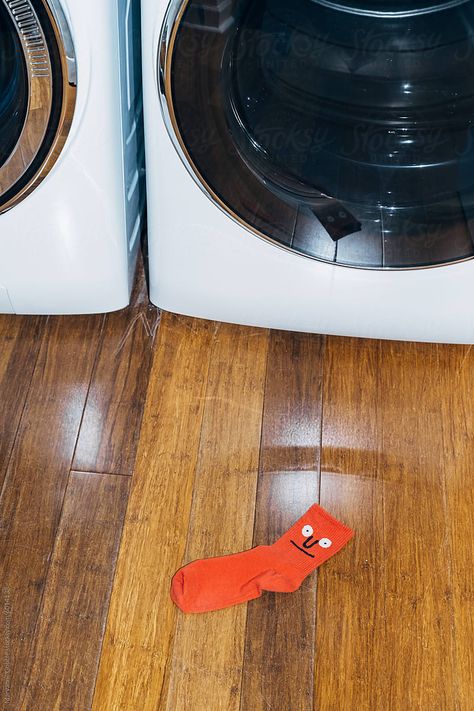 Lost red sock to a pair on the floor next to a washer and dryer.  Direct flash laundry, humor, and housework concept. Dirty Socks Outside, Missing Socks Laundry Room, Lost Socks, Lost, Socks, Stock Photos