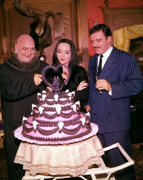 This shot from The Addams Family set looks entirely too colorful and happy. | 12 Jarring Color Images Of Black And White TV Shows Original Addams Family, The Addams Family 1964, Thing Addams, Addams Family Tv Show, John Astin, Los Addams, Uncle Fester, Charles Addams, Happy Cake