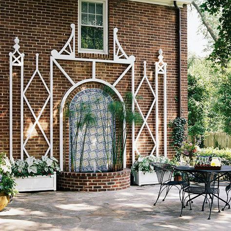 With the right framework, a trellis will fit in any garden or outdoor living space around your home. The clean white framework of this trellis stands out against the dark red brick that serves as a backdrop. The arched center surrounds a flowing water feature that adds to the serene appeal of the outdoor décor. Wall Mounted Trellis, Pergola Cost, Wall Trellis, White Trellis, Arbors Trellis, Trellis Ideas, Building A Pergola, Garden Arbor, Wooden Pergola