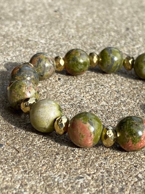 A bracelet made up of unakite bead and small gold-colored beads. The one shown in the picture is a medium sized bracelet. The string is stretchy so it will fit all sized wrists depending on what size you choose from. Earthy Agate Gemstone Beaded Bracelets, Earthy 8mm Beads Bracelet, Earthy Agate Beaded Bracelet For Meditation, Brown Agate Gemstone Beaded Bracelet, Unakite Bracelet, Polished Brown Agate Beads, The One Show, A Bracelet, Bracelet Jewelry