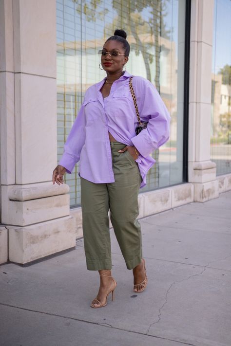 A black woman wearing a lilac oversized button up, army green relaxed chino style pants, nude strappy heels, and a tweed bag Mens Button Down Outfit Women, Mens Button Down Outfit, Button Down Outfit Women, Button Up Outfit, Button Down Outfit, Oversized Outfit, Relaxed Outfit, Chino Pants, Spring Summer Outfits