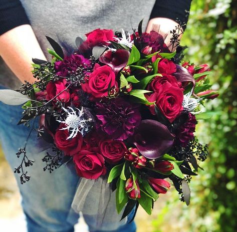 Deep red roses, black cally lilies, seeded eucalyptus painted black, thistle painted silvery white, red alstromeria, and deep, dark purple carnations combined to make this Halloween inspired bouquet. Purple Roses Wedding, Plum Wedding Flowers, Wedding Color Schemes Purple, Rose Centerpieces Wedding, Gothic Love, Purple Flower Bouquet, Purple Carnations, Thanksgiving Flowers, Dark Purple Flowers