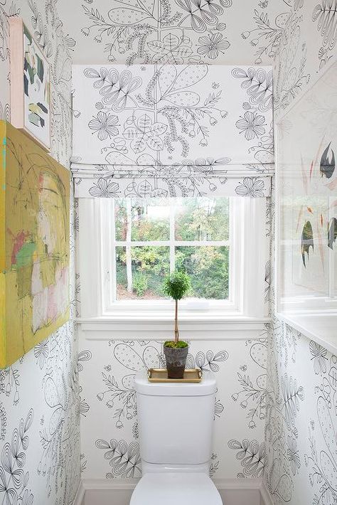 Covered in black and white wallpaper, this charming water closet features a window covered in a black and white floral roman shade hung over a white porcelain toilet, as abstract art provides pops of color to the walls. Water Closet With Window Above Toilet, Water Closet With Window, Window Behind Toilet, Water Closet Design, Water Closet Door, Closet With Window, Black Framed Windows, Antique Brass Door Knobs, Vintage Clawfoot Tub