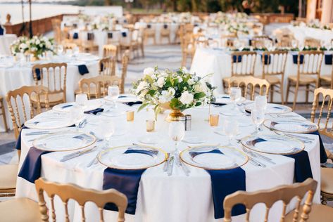 Classic Elegant Wedding Reception Decor, Round Tables with White Tablecloths and Navy Blue Linens, Gold Chairs, White and Greenery Floral Low Centerpieces | Sarasota Historic Waterfront Wedding Venue Ca d’Zan at The Ringling Museum | Tampa Bay Wedding Planner NK Productions Wedding Table Blue And Gold, Navy And Gold Wedding Centerpieces, Classic Elegant Wedding Reception, White And Navy Blue Wedding, Gold And Navy Blue Wedding, Navy Blue Napkins, Gold Chairs, Blue Wedding Receptions, Navy Table