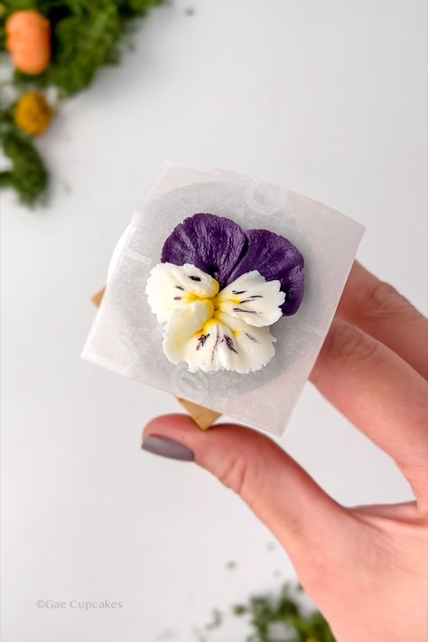 Learn how to pipe these pretty buttercream pansies! Gae Cupcakes has made it easy with realistic buttercream flowers that can be hand-piped onto cupcakes and made to look like real flowers. Click the link to view the buttercream piping tutorial. Follow us on Pinterest and Instagram for more buttercream flowers! Buttercream Pansies Tutorial, Buttercream Spring Flowers, Piping Techniques Flowers, Buttercream Pansies, Buttercream Butterfly, Buttercream Painting, Piped Flowers, Buttercream Flowers Cupcakes, Buttercream Flowers Tutorial