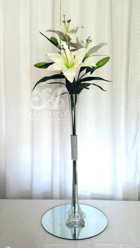 Simple & Elegant Wedding centrepiece: 60cm clear eiffel vase, Diamante bling band, white asiatic lillies, mirror base Centerpieces With Mirror Base, Mirror Centerpiece, Lily Centerpieces, Elegant Wedding Centerpiece, Candle Wedding Centerpieces, Lily Wedding, Simple Elegant Wedding, Crystal Candle Holder, Vase Centerpieces