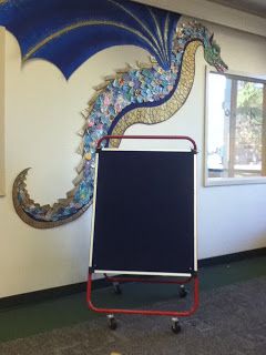 How in the world did they make this dragon? OMG-he is beautiful! Dragon Display Classroom, Fairytale Library Display, Fairy Tale Display, Medieval Classroom Theme, Fantasy Themed Classroom, Fantasy Classroom Theme, Dragon Classroom Theme, Fantasy Classroom Decor, Dragon Bulletin Board