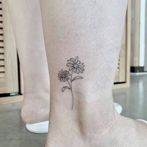 Pure and innocent — that's how people imagine chamomile, and this is one of its main meanings. But there are others. What are they? Read our article. Bonus: 60 cool daisy tattoo ideas you'll love. Shaded Daisy Tattoo, Daisy Tattoo On Ankle, Small Daisy Tattoo On Wrist Simple, 2 Daisy Tattoo, Two Daisy Tattoo, Daisy Fine Line Tattoo, Fine Line Daisy Tattoo, Gerber Daisy Tattoo, Daisy Tattoo Ideas