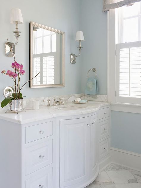 Dream Bath in Blue: Separate Spaces A pair of long vanities flanks each side of the entrance from the master bedroom. Separate vanities have made it easier for the two homeowners to share a bath without bumping in to each other while they get ready in the morning. Curved fronts give the vanities a graceful appearance that complements the elegant lines featured on the bathtub. Blue Powder Room, L Shaped Bathroom, Mom Bathroom, Light Blue Bathroom, Elegant Bathroom Decor, Spare Bathroom, House Upgrades, Elegant Bath, Bathroom Paint