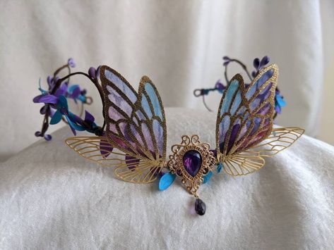 This beautiful tiara features a purple teardrop charm surrounded by gold, purple, and teal faerie wings. Purple and teal leaves surround the base, and berries swirl around the piece. Perfect for special occasions or to bring a little magic to your every day! Butterfly Tiara, Woodland Tiara, Faerie Wings, Fairy Crown, Beautiful Tiaras, Magical Jewelry, Fantasy Jewelry, Tiaras And Crowns, Fantasy Clothing