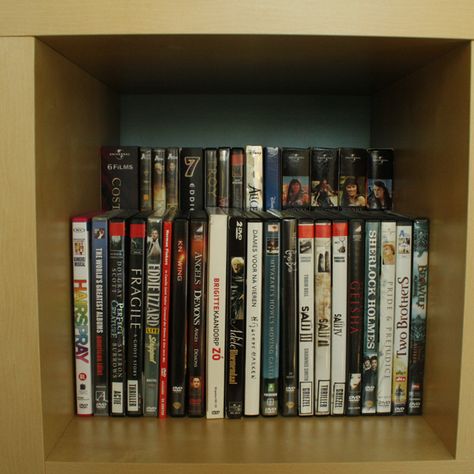 Double DVD storage space by placing a raised shelf (this one is a wood shelf sitting on top of upside down large candle holders - but could use anything) in the back of a bookcase ... clever! Dvd Storage Ideas Diy, Ikea Dvd Storage, Dvd Storage Tower, Dvd Storage Ideas, Dvd Storage Cabinet, Diy Dvd Storage, Diy Dvd, Dvd Storage Shelves, Dvd Cabinets