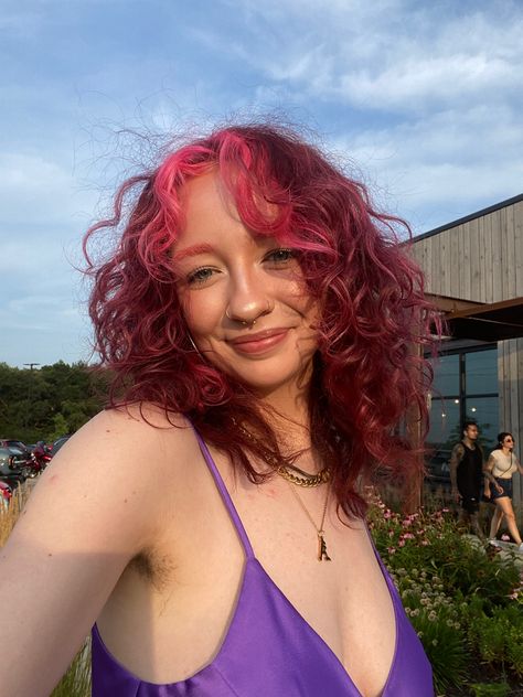 pink hair, curls, pink curls, red hair, red curls, pink bangs, pink money piece, short hair, hair color, fun color, purple dress, satin dress, gold jewelry, nose ring, septum, glowy makeup, simple makeup, pink eyebrows red hair, pink hair, hair inspo, pink bangs, pink eyebrows, gold jewelry, gold nose ring, gold septum ring, summer hair Dark Hair Pink Money Piece, Purple Hair Pink Money Piece, Pink And Purple Curly Hair, Pink Hair Money Piece, Burgundy Money Piece Hair, Pink Hair With Money Piece, Red Hair With Pink Money Piece, Red Hair Pink Money Piece, Pinky Red Hair