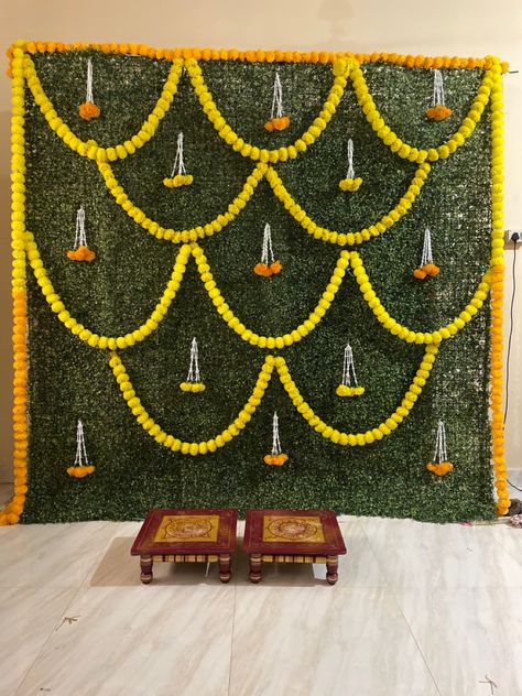 Traditional Indian Backdrop Decor, Green Mat Backdrop Decoration, Marigold Backdrop Decoration, Grass Decoration For Ganpati, Kelvan Ceremony Decoration At Home, Marigold Flower Decoration Backdrop, Simple Stage Decorations At Home, Simple Flower Decorations Indian, Grass Backdrop With Flowers