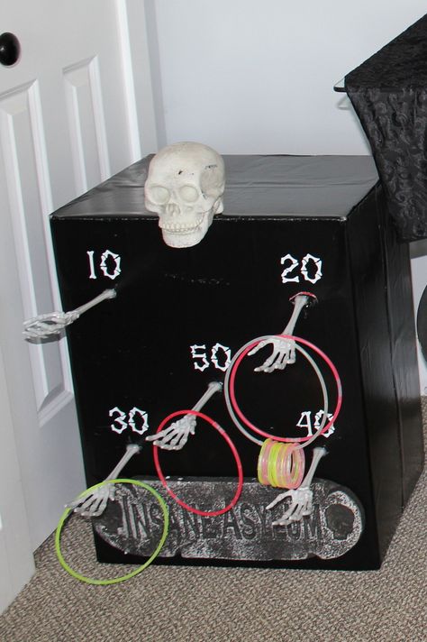 Michael’s Halloween Crafts, Diy Cardboard Halloween Games, Halloween Trick Or Treat Ideas At Home, Skeleton Ring Toss, Carnevil Halloween Party Games, Skull Toss Carnival Game, Kids Halloween Carnival Games, Halloween Whats In The Box Game, Halloween Ring Toss Game Diy