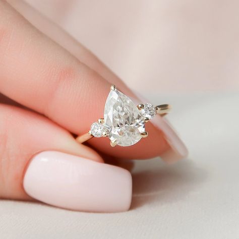 3.75 Ct Elongated Pear Cut Moissanite Engagement Ring, Pear Cut Ring, Moissanite Engagement Ring, Pear Engagement Ring ✥ 𝐌𝐚𝐢𝐧 𝐒𝐭𝐨𝐧𝐞 𝐃𝐞𝐭𝐚𝐢𝐥𝐬 ↣ Shape: Pear Cut ↣ Type: Moissanite ↣ Weight: 3.75 Ct Pear (App.) ↣ Color: Colorless ↣ Side Stone: Moissanite ↣ Clarity: VVS ↣ Making Process: Handmade - Crafted by our experienced team ✥ 𝐑𝐢𝐧𝐠 𝐃𝐞𝐭𝐚𝐢𝐥𝐬 ↣ Band Width: 1.8 mm (± 0.10) [Customization Possible] ↣ Metal Purity: Solid Gold (10KT, 14KT, 18KT); Silver (925 Sterling), 950 Pl Pear Moissanite Engagement Ring, Pear Diamond Rings, Moissanite Diamond Rings, Three Stone Engagement, Three Stone Engagement Rings, Moissanite Wedding Bands, Pear Diamond, Pretty Rings, Three Stone Rings