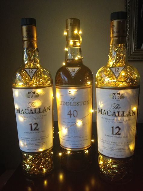 Macallan Scotch whiskey bottle centerpieces party decorations, 40th birthday. Large (empty) 1.75 L macallan bottles filled with fairy lights and gold metallic shred. Balloon Topiary, 40th Bday Ideas, Birthday Party Decorations For Adults, Bottle Centerpieces, Led Fairy String Lights, Glitter Glasses, 70th Birthday Parties, Birthday Centerpieces, Bar Party