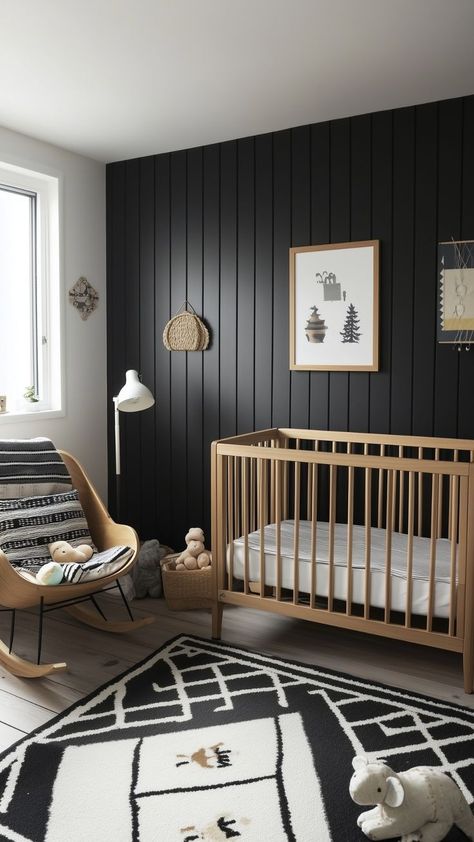 A Scandinavian-inspired nursery with a black vertical panel accent wall, a natural wood crib, and a light wood rocking chair with monochrome striped cushions. The space is accented with a black-and-white geometric rug, simple wall art, and cozy toys. Nursery Ideas Modern Farmhouse, Goth Baby Room, Black And White Nursery Boy, Black Crib Nursery, Moody Nursery, Black Nursery Ideas, Rocker Nursery, Tan Nursery, Modern Gender Neutral Nursery