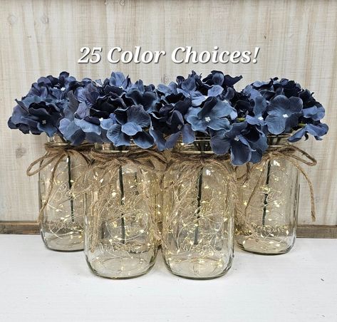 This six piece set includes your choice of hydrangea color. Choose pint size or quart size...or a set of both. Each centerpiece jar includes one set of warm white LED fairy lights, and one silk hydrangea, and a jute bow.  These centerpieces are very popular for weddings, baby showers, parties, corporate events, holiday events, and any other event that requires table centerpieces. They also look great in any room of your house or office. To see other lighted jar options and all of my other listin Lighted Mason Jar Centerpieces, Dusty Blue Hydrangea, Mason Jars With Lights, Event Centerpieces, Blue Centerpieces, Dried Flowers Wedding, Hydrangea Colors, Jar Centerpieces, Event Centerpiece