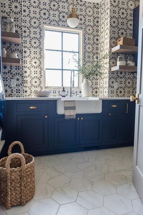 White hex floor tiles contrast navy blue shaker laundry room cabinets accented with brass hardware and a white countertop holding a farmhouse sink with a stainless steel pull out faucet. Kitchen Floor Tiles With Blue Cabinets, Shaker Laundry, Blue Laundry Rooms, White Countertop, Patterned Tile, Laundry Cabinets, Farmhouse Laundry Room, Laundry Room Cabinets, New Kitchen Cabinets