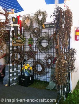 Here's a great use of gridwalls.        This booth was in a nice corner location, so hanging some wreaths on the outside of the gridwall panel allows customers approaching the booth from that side to see the items. Wreath Display Ideas, Wreath Display, Craft Booths, Craft Displays, Craft Fair Booth Display, Christmas Booth, Craft Show Booths, Craft Show Booth, Wreath Storage