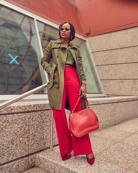 A black woman in a color-blocked outfit. She is wearing red pants and an army green shirt and trench coat with a red Louis Vuitton handbag. Red And Army Green Outfits, Army Green Shirt Outfit, Poncho Outfit Fall, Khaki Street Style, Army Green Trench Coat, Olive Green Trench Coat, Army Green Outfit, Office Routine, Olive Green Pants Outfit