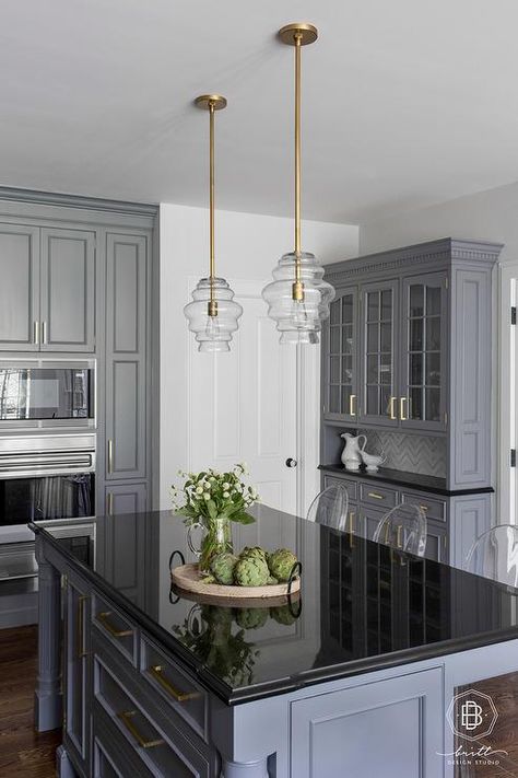 Gray kitchen island featuring a black quartz countertop under a set of mini glass and brass lanterns fitted with ghost counter stools. Black Quartz Countertop, Gray Kitchen Island, Kitchen Black Counter, Black And Grey Kitchen, Black Kitchen Countertops, Grey Kitchen Island, Grey Kitchen Designs, Black Countertops, Stools For Kitchen Island