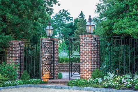 Brick pillars adorned with wrought-iron fencing create a stately side entry. Brick Pillars, Estate Gardens, Fountain Garden, Brick Columns, Fence Plants, Cedar Garden, Living Fence, Brick Fence, Home Design Magazines