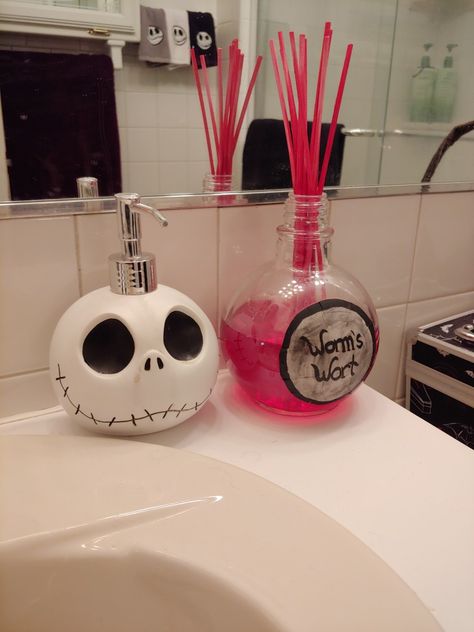 Jack Skellington soap dispenser purchased from Spirit Halloween. Beware that paint wears off, as you can see in photo. Oil diffuser made from empty/cleaned bottle of Captain Morgan Bombshell. "Worms Wort" hand painted on thick paper and sealed to bottle. Oil and reeds purchased from Walmart for under $5. Nightmare Before Christmas Bathroom Casa Disney, Nightmare Before Christmas Decorations, Halloween Bathroom, Nightmare Before Christmas Halloween, Christmas Bathroom, Goth Home, Goth Home Decor, Gothic Decor, Gothic Home Decor