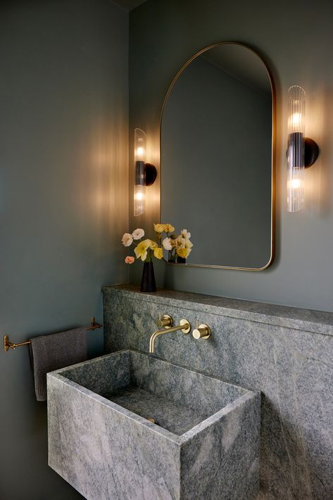 Elevated minimalism at its finest! This powder room design exudes modern luxury with its stunning green marble sink, brushed brass fixtures, and a softly arched gold mirror framed by chic wall sconces. The muted green walls and fresh florals add a calming touch to this serene space. Perfect inspiration for anyone seeking a sophisticated yet inviting vibe for their home! #BathroomGoals #ModernDesign #LuxuryInteriors #MarbleLove #GreenBathroom #HomeInspiration #InteriorStyling #ElegantSpaces Gold Framed Mirror, Powder Room Design, Marble Sinks, Bathroom Goals, Brass Fixtures, Green Bathroom, Green Marble, Green Wall, Gold Mirror