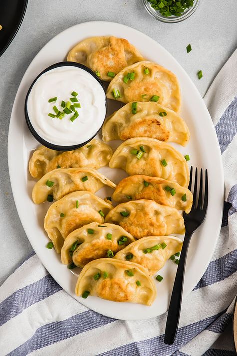 Pierogi topped with chives on a white plate next to a blue napkin Potato And Cheese Pierogi, Cheese Pierogi Recipe, Pierogi Filling, Bread Loafs, Polish Dumplings, Vegetarian Appetizer, Pierogi Recipe, Potato Cheese, Vegetarian Nutrition