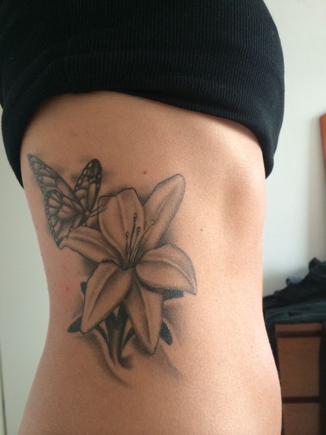 Lily Tattoo Design On Ribs, Water Lily Butterfly Tattoo, Flower On Side Tattoo, Lily With Butterfly Tattoo, Lily And Butterfly Tattoo, Grey Butterfly Tattoo, Black And Grey Butterfly Tattoo, Black And Grey Butterfly, Flower Rib Tattoo