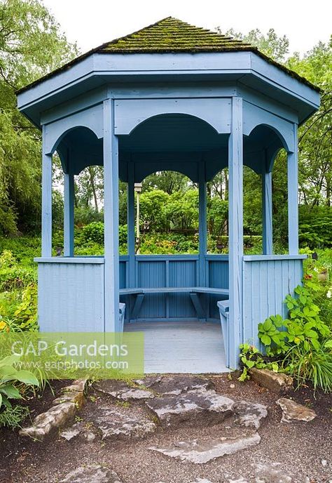 Blue painted wooden gazebo with built-in sitting benches and cedar shingles covered in green Bryophyta - Moss overlooking pond in summer, Centre de la Nature public garden, Saint-Vincent-de-Paul, Laval, Quebec, Canada Painted Gazebo, Wooden Gazebo, Cedar Shingles, Saint Vincent, Slate Roof, Plant Photography, Public Garden, Quebec Canada, Blue Paint