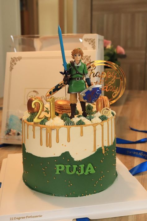 A beautiful birthday cake coloured in green, white, and a dripping gold border, topped with golden macarons and a figurine of Link. Tears Of The Kingdom Cake Ideas, Link Cake Zelda, Zelda Cakes Birthday, Nerdy Birthday Cakes, Zelda Tears Of The Kingdom Cake, Legend Of Zelda Birthday Cake, Zelda Cake Ideas, Legend Of Zelda Birthday Party Ideas, Zelda Birthday Party Decorations