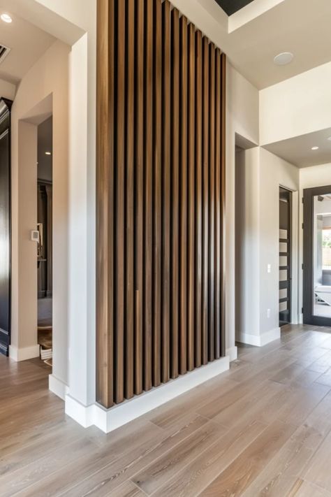 Modern home interior showcasing a wooden slatted room divider integrating with a structural column, against a backdrop of light hardwood floors and white walls. Slat Wall With Black Wall, Slatted Wood Accent Wall, Entry Way Feature Wall Ideas, Mountain Accent Wall Wood, Wood Wall Accent Ideas, Slat Wall Ideas Living Room, Slat Wall Living Room, Wood Slats Accent Wall, Trim Accent Wall Ideas