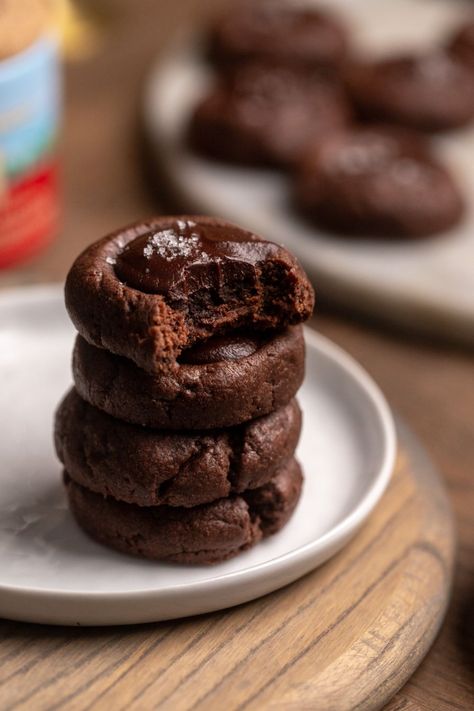 A stack of chocolate cookies on a white plate with a bite taken out of the top cookie. Chocolate Shortbread Cookies Christmas, Dark Chocolate Thumbprint Cookies, Ganache Cookies, Chocolate Ganache Cheesecake, Caramel Ganache, Chocolate Thumbprint Cookies, Shortbread Cookies Christmas, Chocolate Shortbread, Chocolate Shortbread Cookies